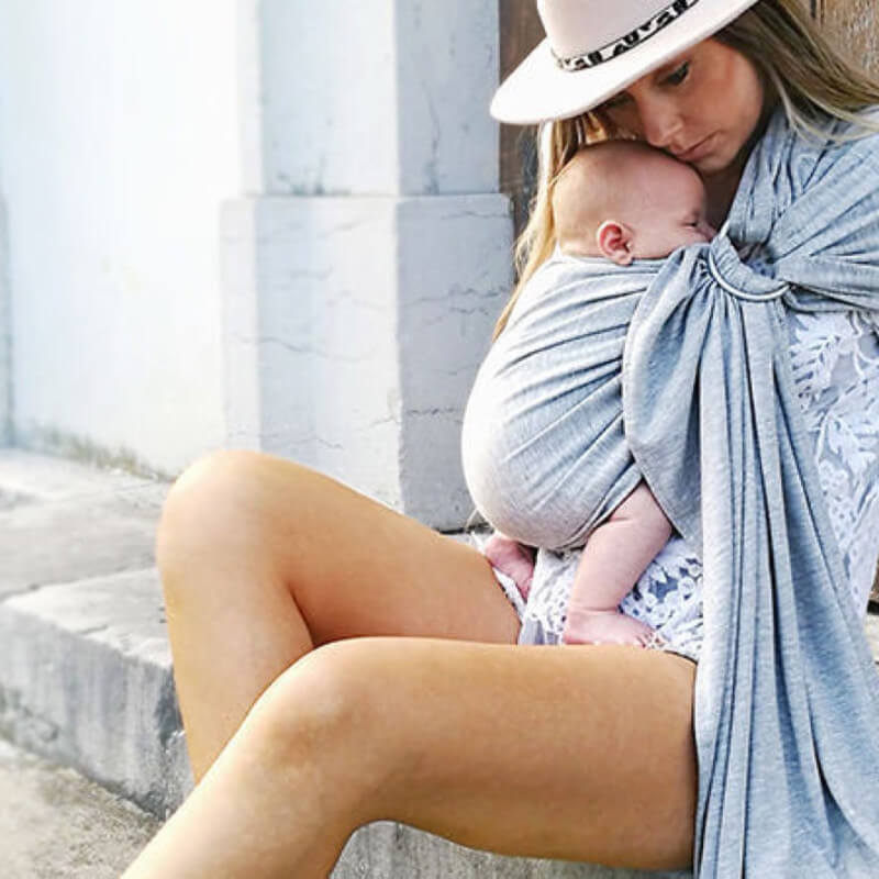 Mother carrying baby with Love Radius mottled blue baby wrap outdoors