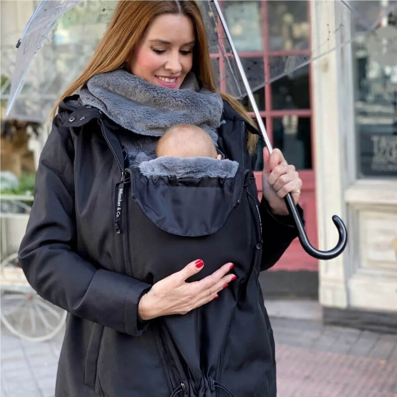 Płaszcz do noszenia Wombat & Co Wallaby 2.0 czarny, mama niosąca dziecko pod parasolem