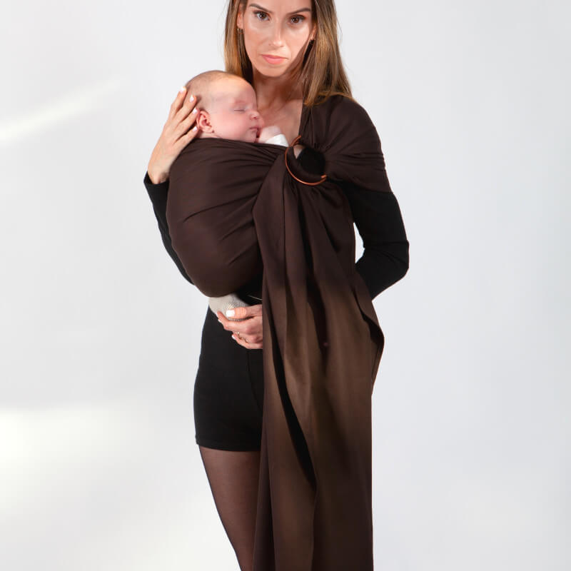Moeder draagt baby in bruine Love Radius sling, veilig gewikkeld weefsel