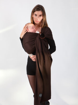 Mother carrying baby in brown Love Radius sling, fabric securely wrapped