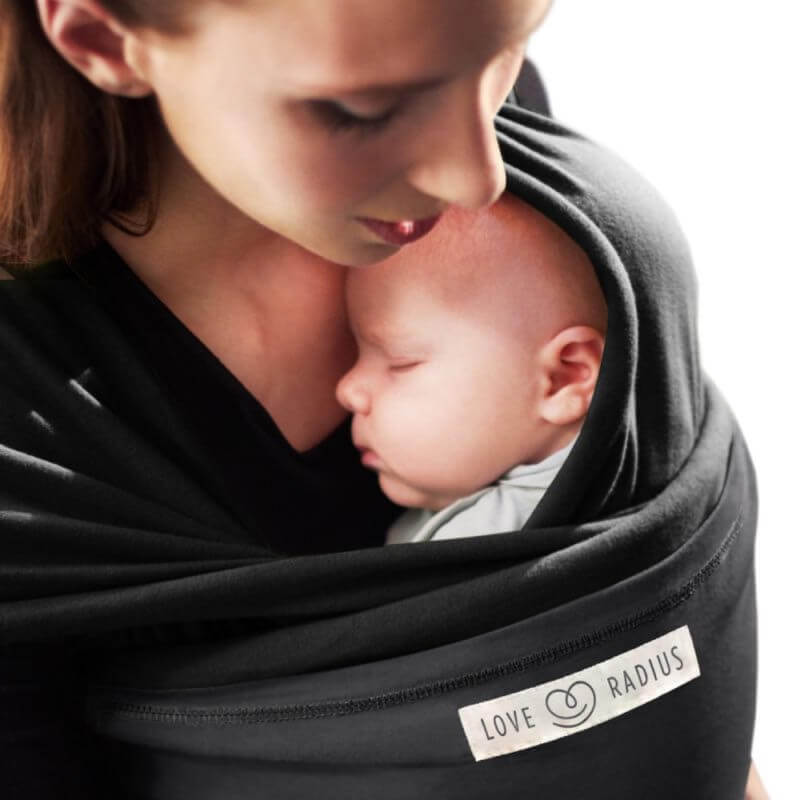 Mãe carregando recém-nascido em echarpe Love Radius L'Originale preta, contato pele a pele íntimo
