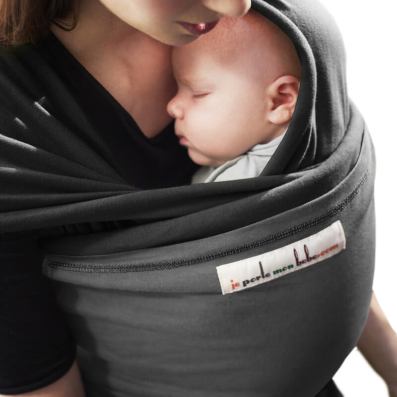 Moeder wikkelend haar baby in de Love Radius L'Originale draagzak zwart