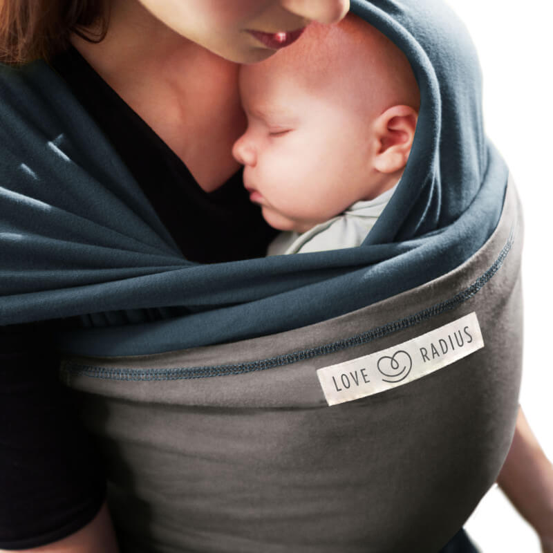 Moeder die baby inswachtelt in Love Radius draagdoek in pauwblauw, close-up tederheid