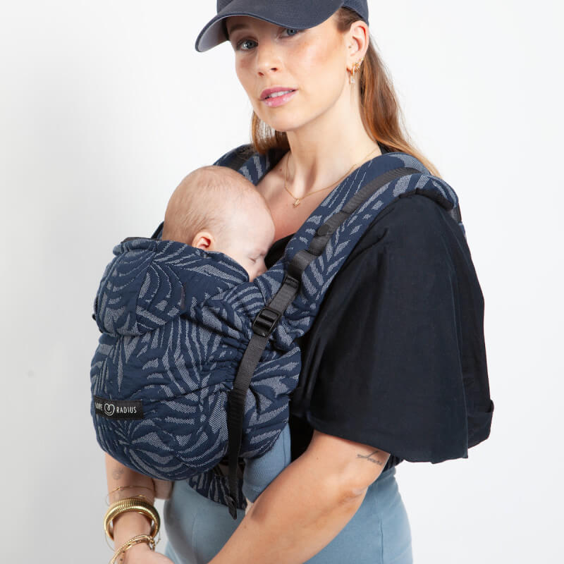 Mamma che indossa neonato in Love Radius HoodieCarrier 2 tropical dark, motivo fogliame blu