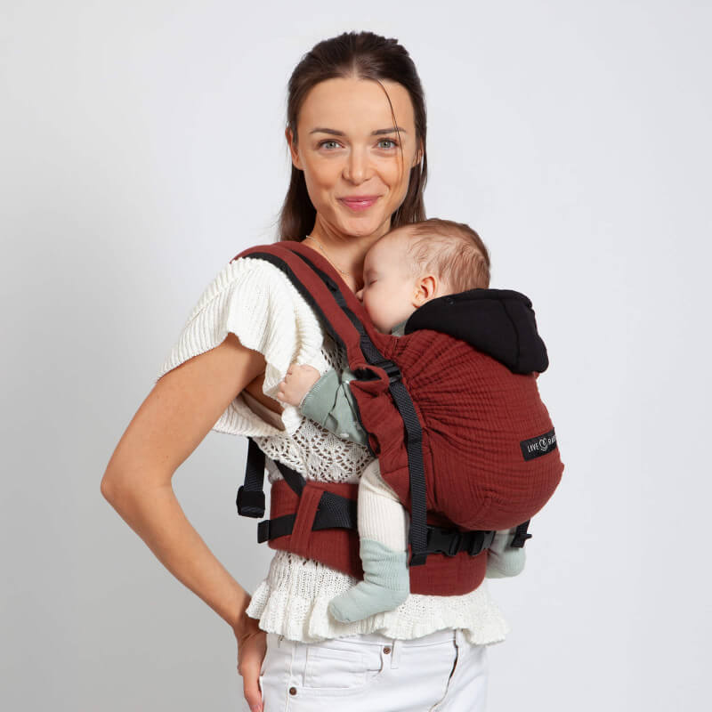 Mamma bär Love Radius HoodieCarrier 2 Hot Paprika med sovande baby mot ryggen