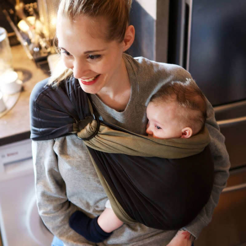 Woman carrying baby in reversible anthracite-olive Love Radius sling, everyday use