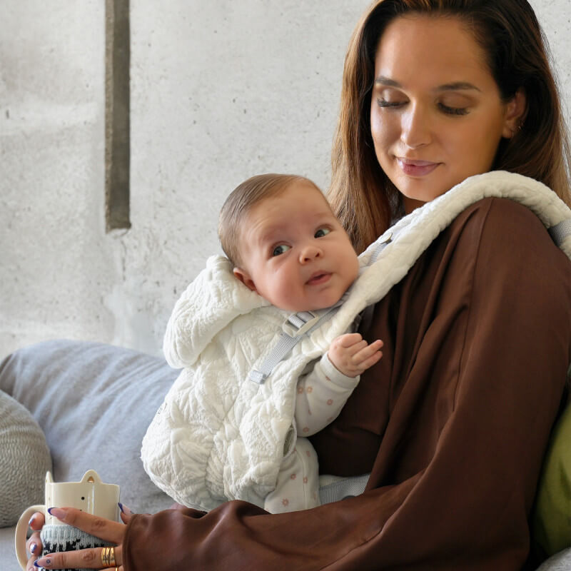 Mamma som bär sitt barn i Love Radius HoodieCarrier 2 Blossom, sedd i profil