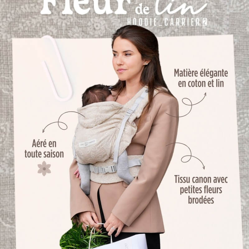 Vrouw draagt Love Radius HoodieCarrier 2 Fleur de Lin babydrager met zuigeling
