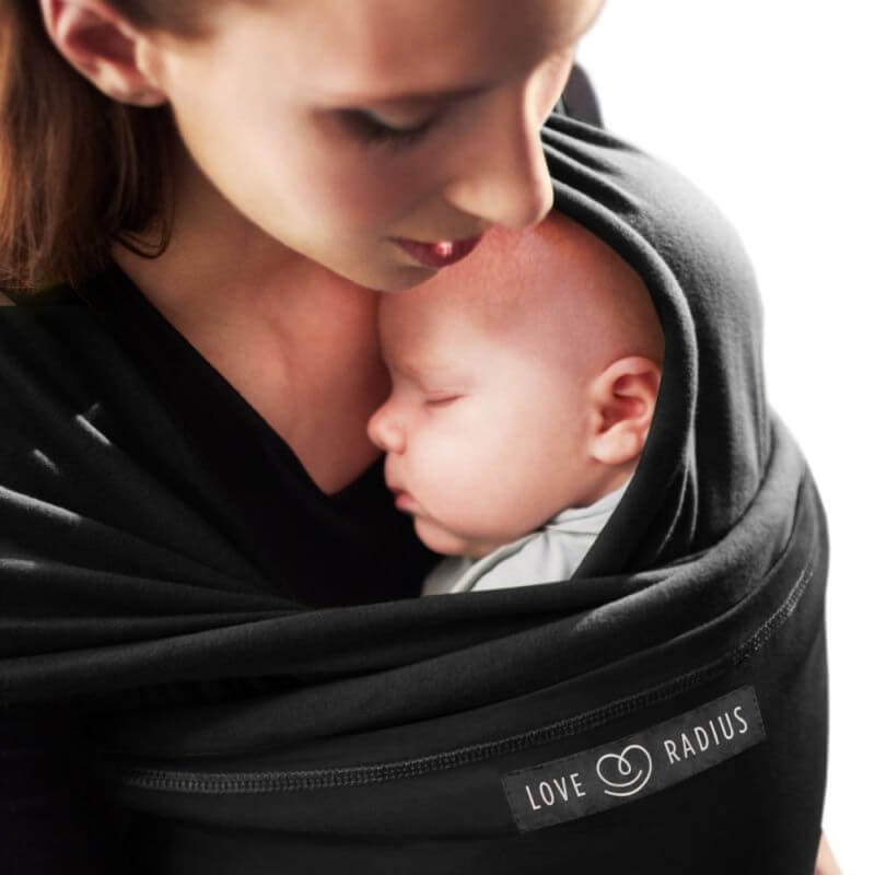 Moeder die haar baby inpakt in de zwarte Love Radius-draagdoek, zijaanzicht close-up