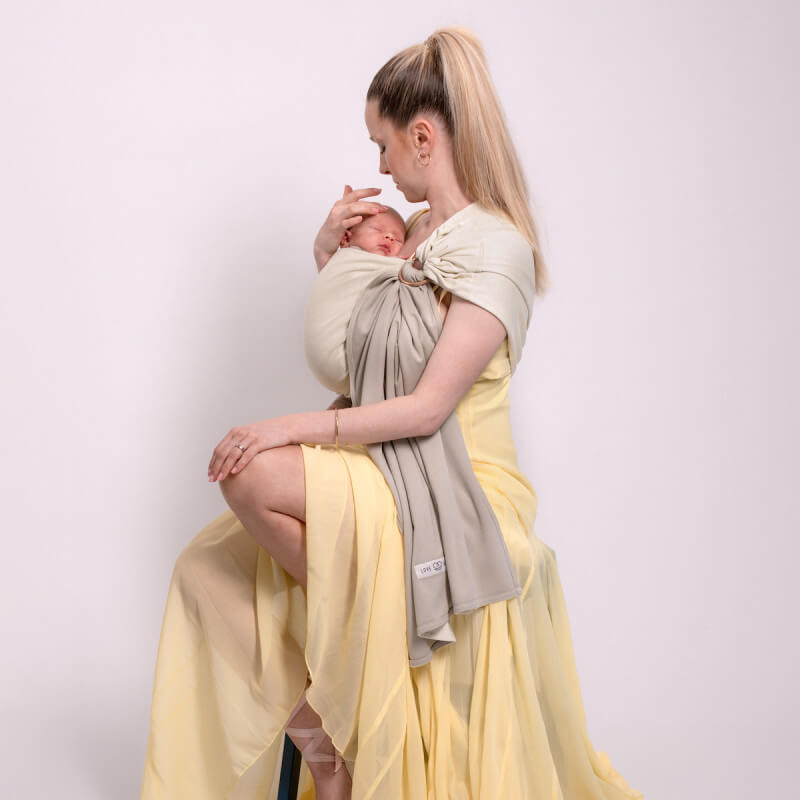 Mamma bär sin nyfödd i reversibel sling Love Radius vanilla-eucalyptus