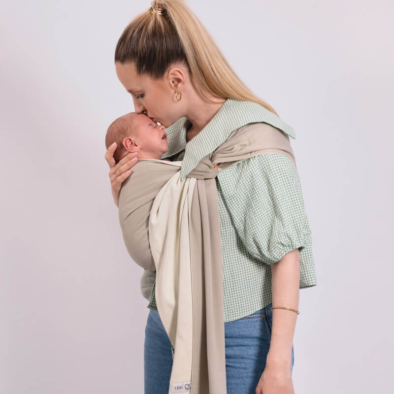 Anya az újszülöttjét a Love Radius Les Imparfaits hordozókendőben viszi, Vanilla Eucalyptus megfordítható színben