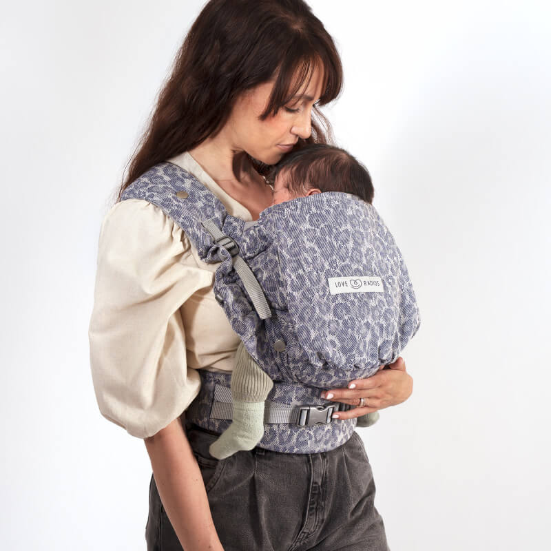 Mutter trägt ihr Neugeborenes in der Love Radius PhysioCarrier 2 Blue Leopard Babytrage