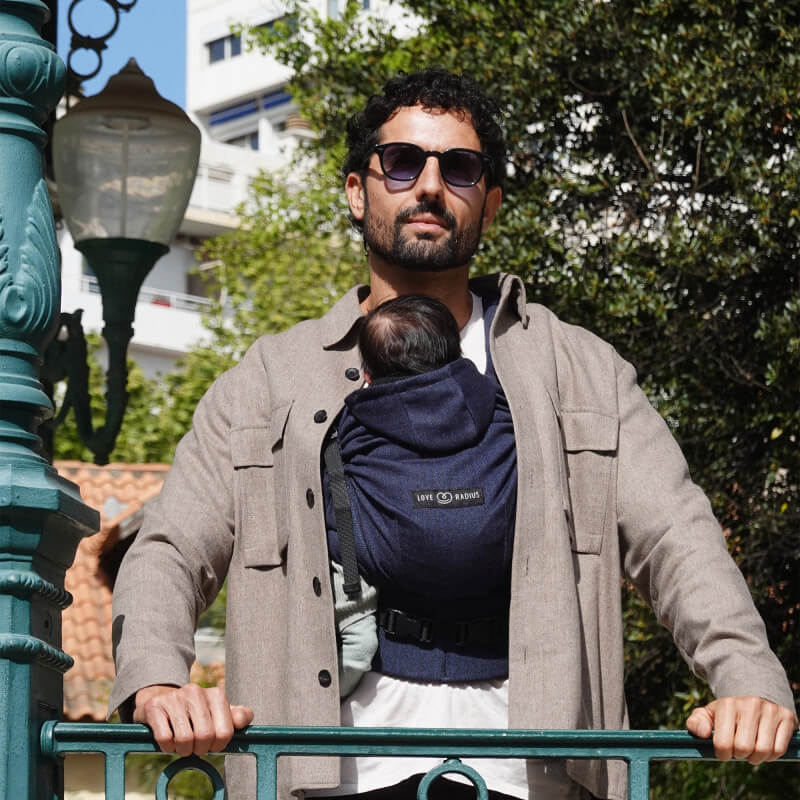 Padre usando Love Radius HoodieCarrier 2 Boyfriend azul marino en entorno urbano soleado