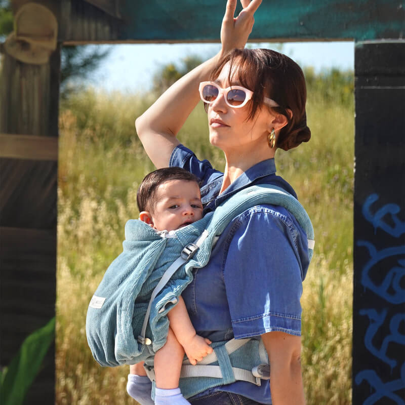 Femme portant porte-bébé Love Radius PhysioCarrier 2 Velvet Blue en situation extérieure